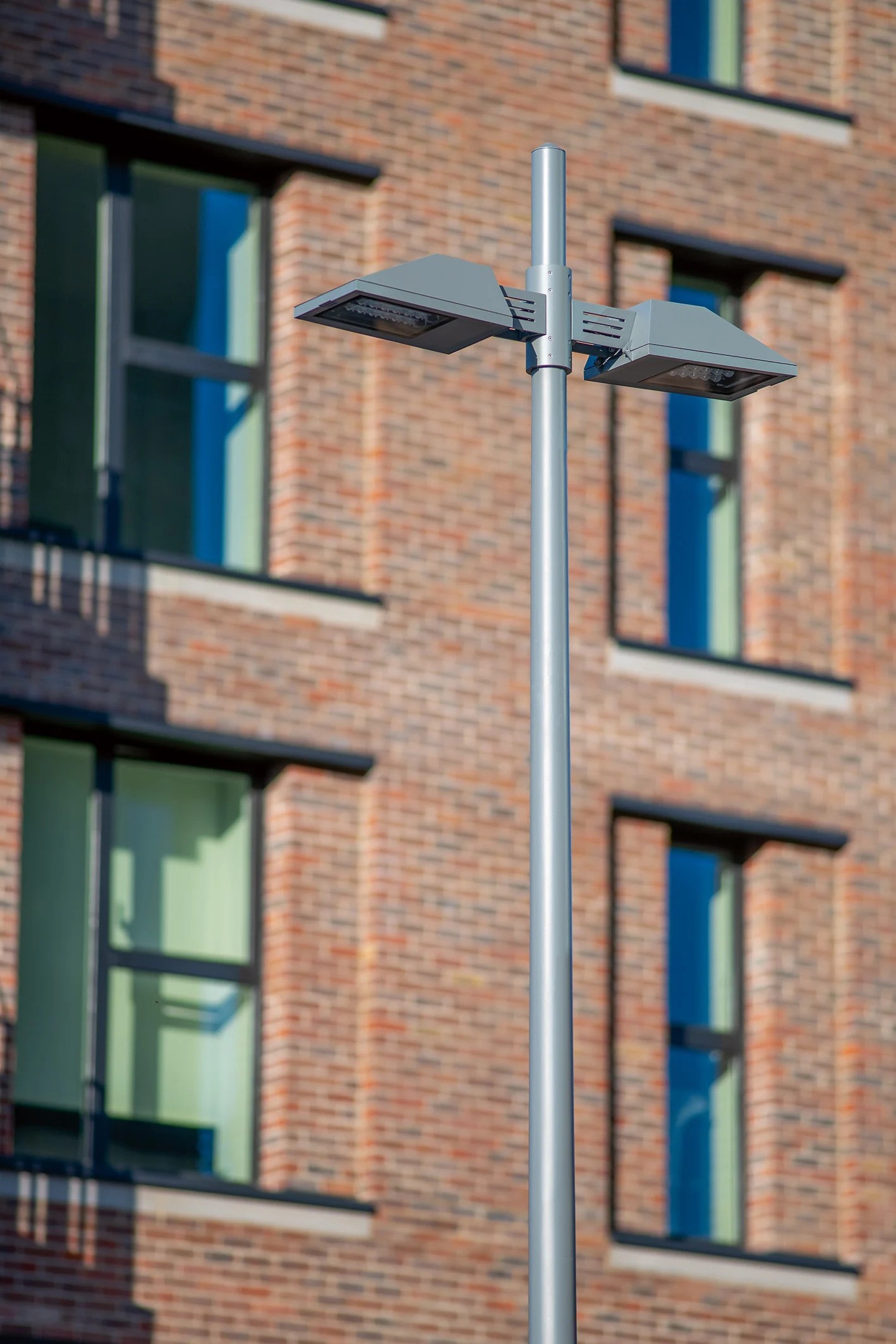 Hale Wharf residential buildings designed by Allies and Morrison showing contemporary tiled facades with urban character, WE-EF PFL230 LED pole-mounted luminaires visible providing pathway lighting for 249-apartment first phase completed June 2021, demonstrating sustainable housing development with BREEAM certification emphasizing environmental compatibility and resource-efficient construction on former industrial site