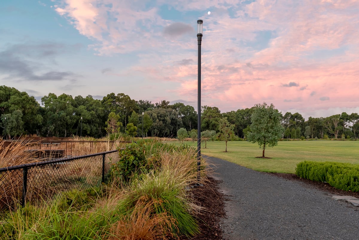 Felixstow Reserve Adelaide walking trail at sunset showing WE-EF ZFT400 LED lantern-style luminaire mounted directly on pole with same diameter creating seamless one-piece aesthetic, modern interpretation of traditional lantern design along 7.6-hectare recreation reserve and River Torrens/Karrawirra Parri ecological corridor, designed to provide secure environment while minimizing glare and light spillage to adjacent dense residential area 6 kilometers from Adelaide city center