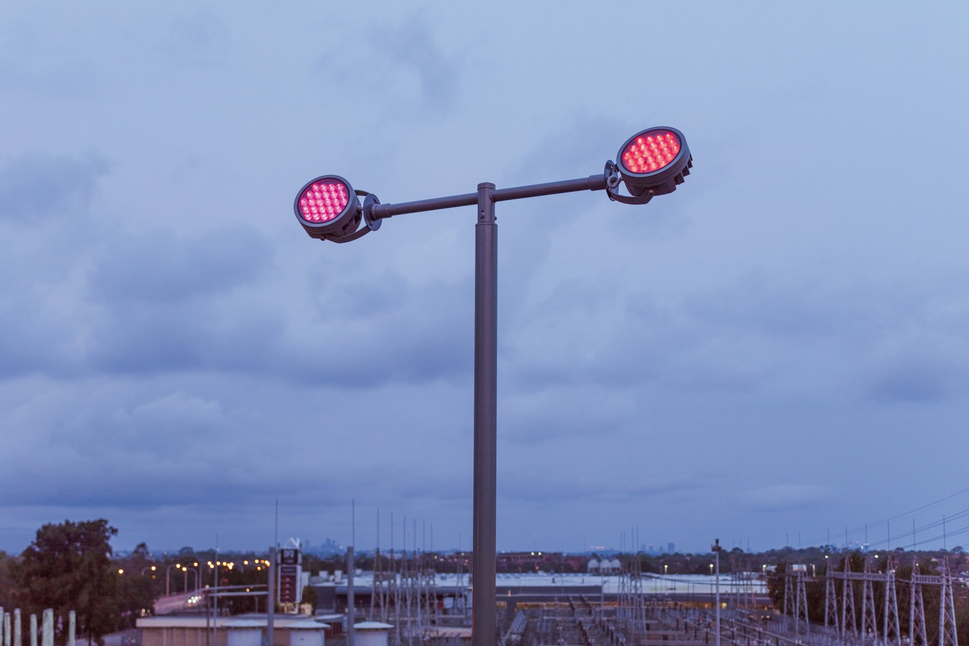 Close-up of WE-EF FLC200-CC RGBW projector luminaires mounted on custom pole system providing flexible beam architectural lighting for public sculpture installation