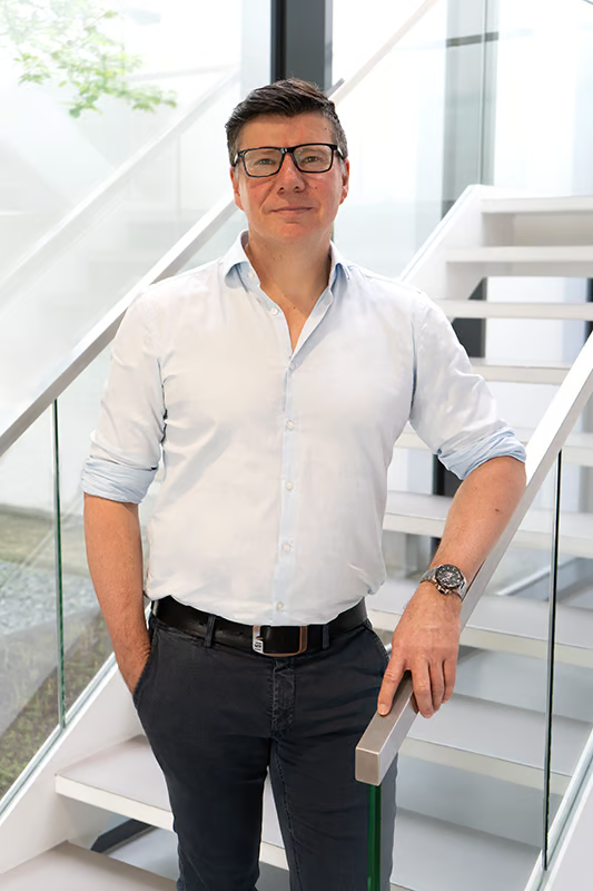 Portrait of Robert Diedrich, Global Head of Marketing at WE-EF Group, leaning on a handrail of a staircase at the company's head office.
