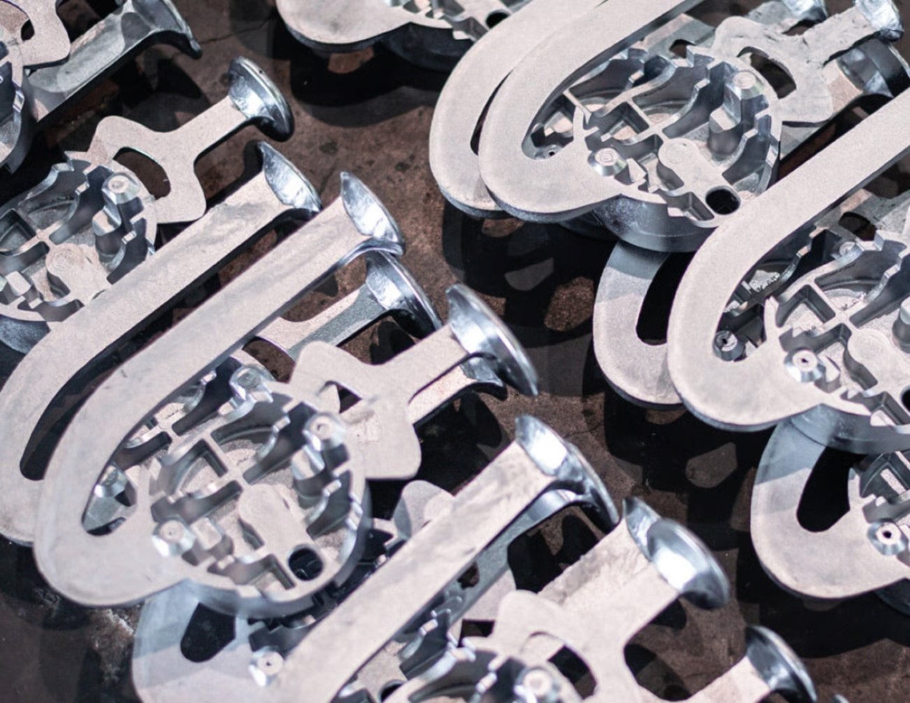 Close-up of freshly cast aluminium luminaire components stacked for further processing, illustrating WE-EF's use of recycled aluminium.