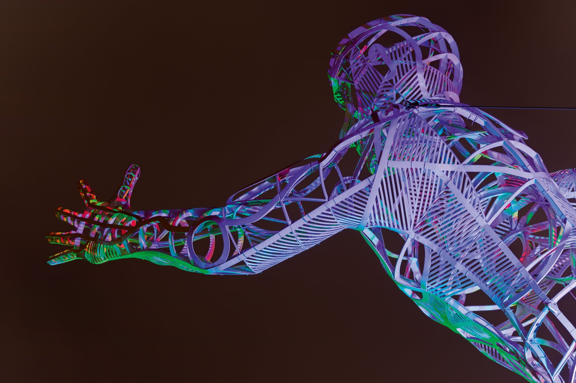 The Sprinter sculpture by Dominique Sutton illuminated with RGBW color-changing LED lighting showing purple and green hues against night sky near Sydney Olympic Park