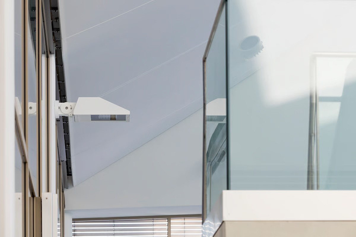 WE-EF PFL540 LED luminaire with asymmetric forward-throw light distribution mounted on wall bracket along longitudinal side of Hamburg-Ohlsdorf pool hall, minimalist striking design harmonizing with Czerner Göttsch Architects' futuristic aesthetic, featuring 5CE Superior Corrosion Protection technology with special protective coating permanently withstanding extreme air humidity, splash water and chlorinated swimming pool environment requiring outdoor-rated ingress protection