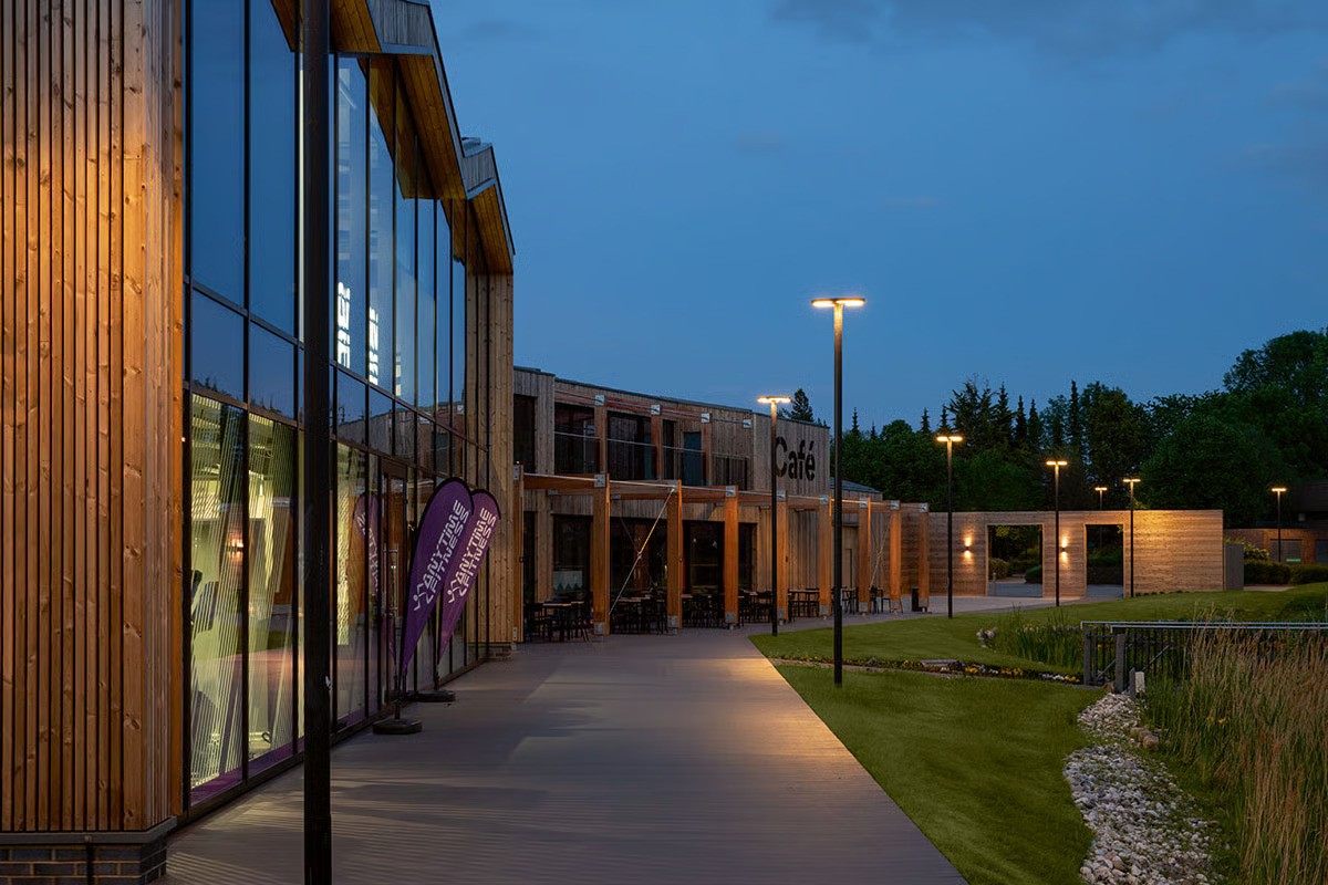 Croxley Park office buildings at blue hour showing comprehensive WE-EF lighting concept developed with ESA architects London, approximately 260 CFT540 ring-shaped pole-mounted luminaires on 5-meter aluminum poles providing safe pleasant illumination across 30+ hectare campus-like site, warm white 3000K temperature creating feel-good atmosphere enabling office park to function as living space beyond working hours, completed as part of three-year investment in redesigned outdoor facilities by Columbia Threadneedle near Watford north of London