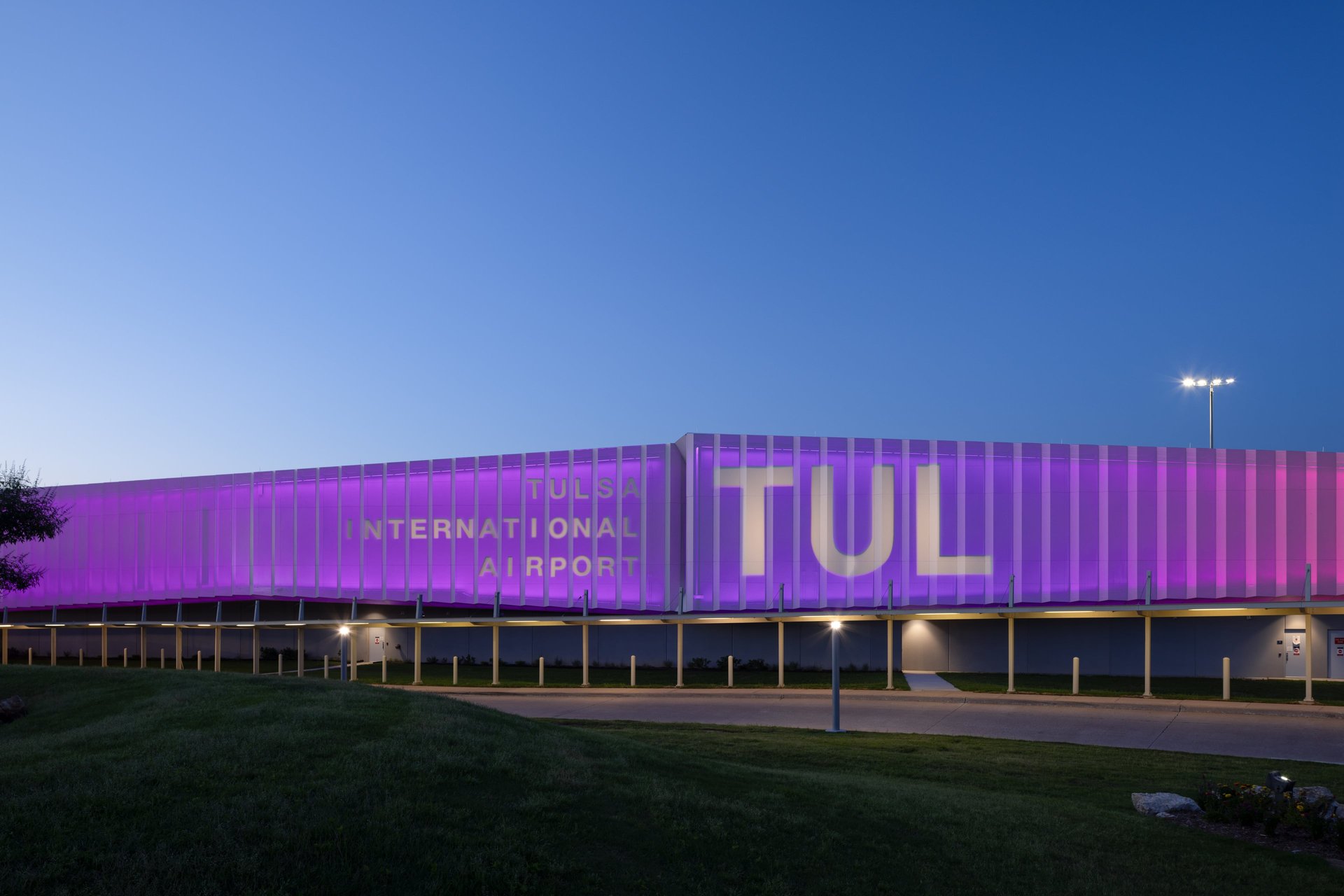 Facade of Tulsa International Airport is lit in purple and pink light.