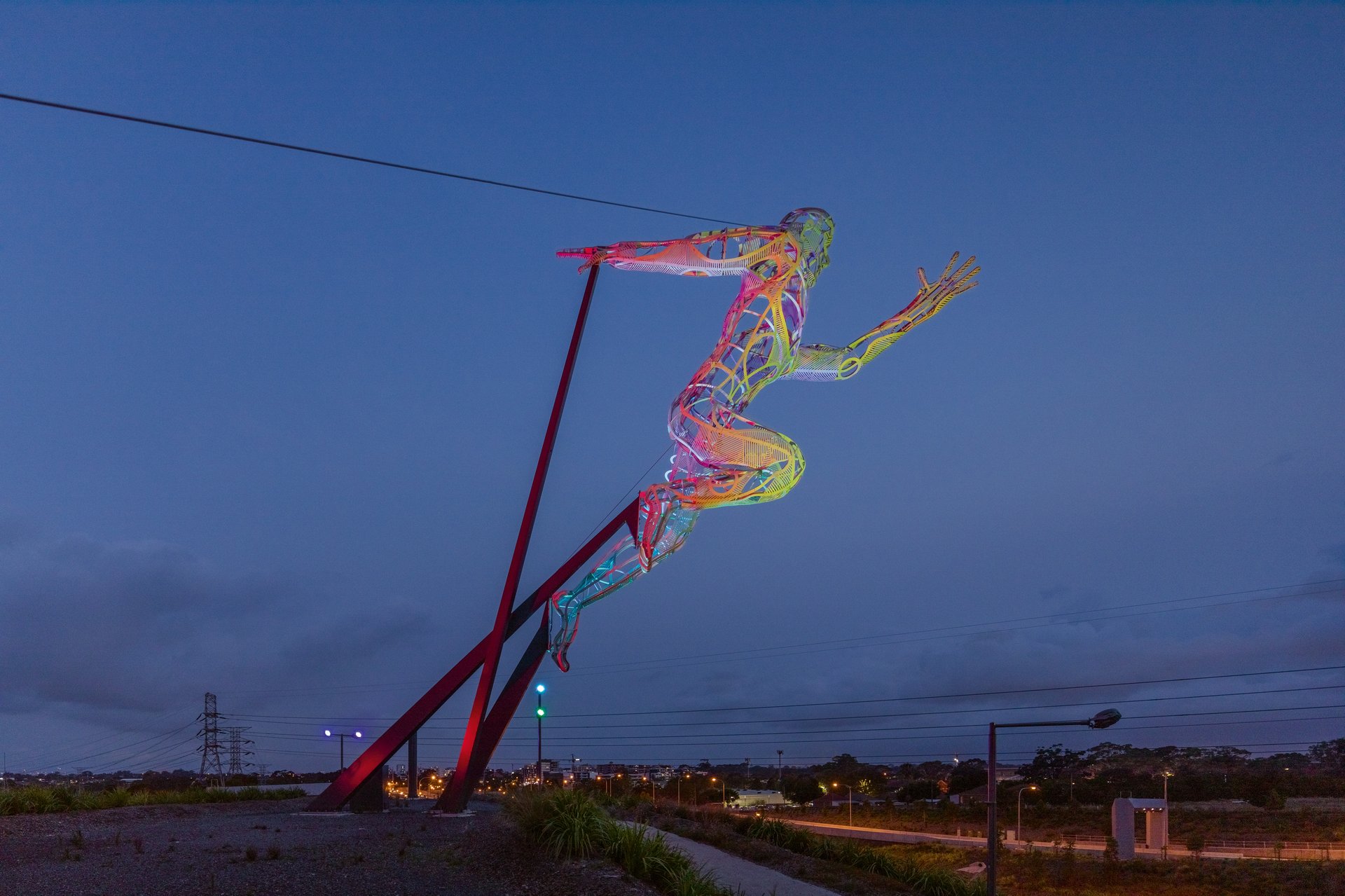 16-meter tall Sprinter sculpture illuminated at dusk along Sydney M4 motorway with WE-EF FLC200-CC projectors creating dynamic multicolor lighting effects