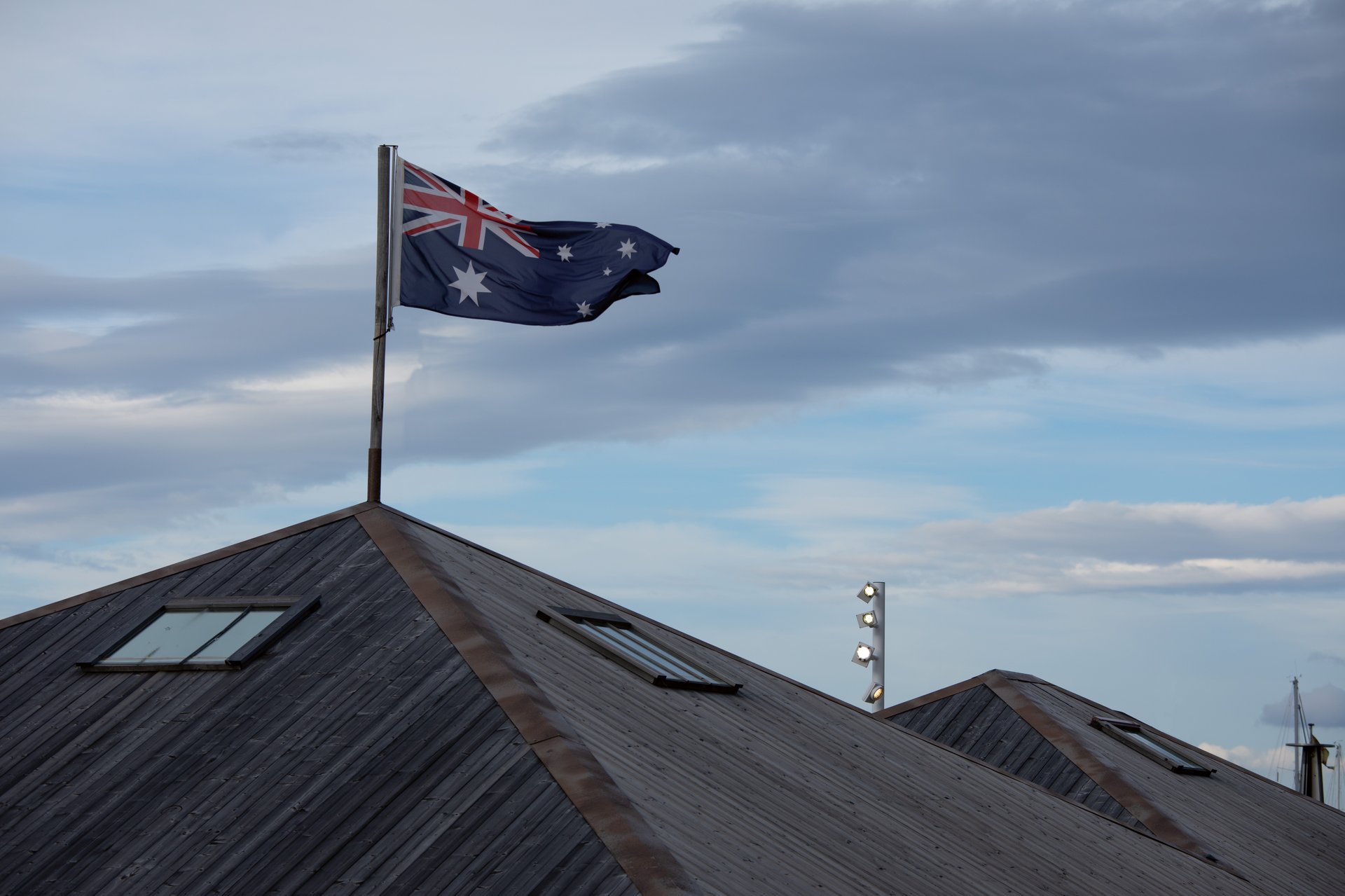 Vue de jour du Mawson’s Huts Replica Museum et du bâtiment voisin Kent & Kent Antiques, avec un mât d’éclairage WE-EF au premier plan, conçu pour illuminer le site la nuit.