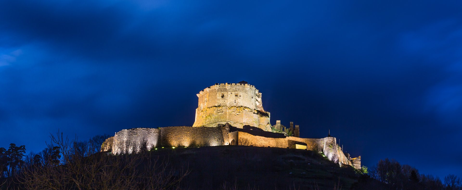 Château de Murol in Auvergne, France, its medieval keep and ramparts floodlit on a hilltop at night
