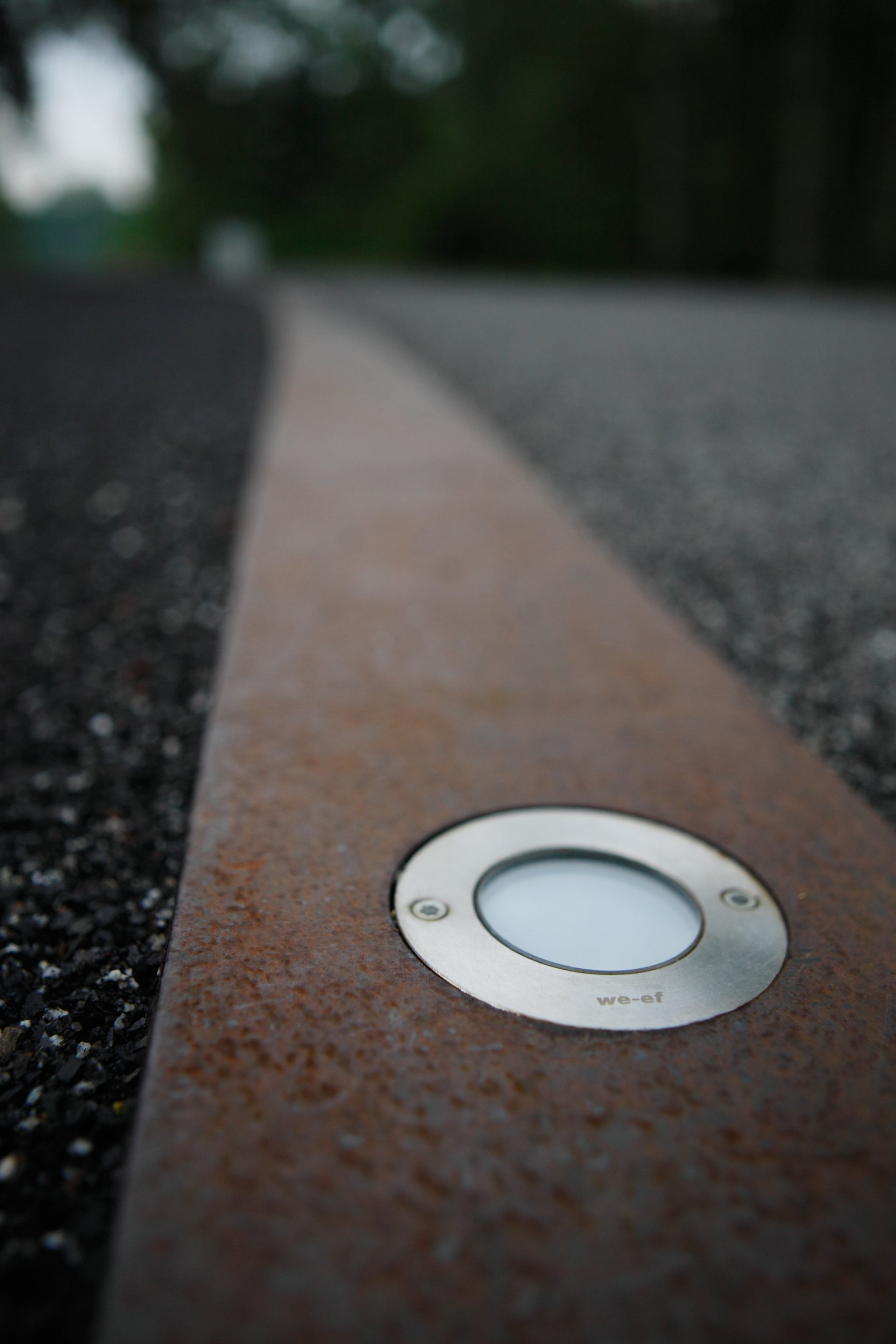 Close-up of a WE-EF ETC119 LED inground uplight flush-mounted into a Corten steel band along the ring promenade path at Zeche Zollverein in Essen