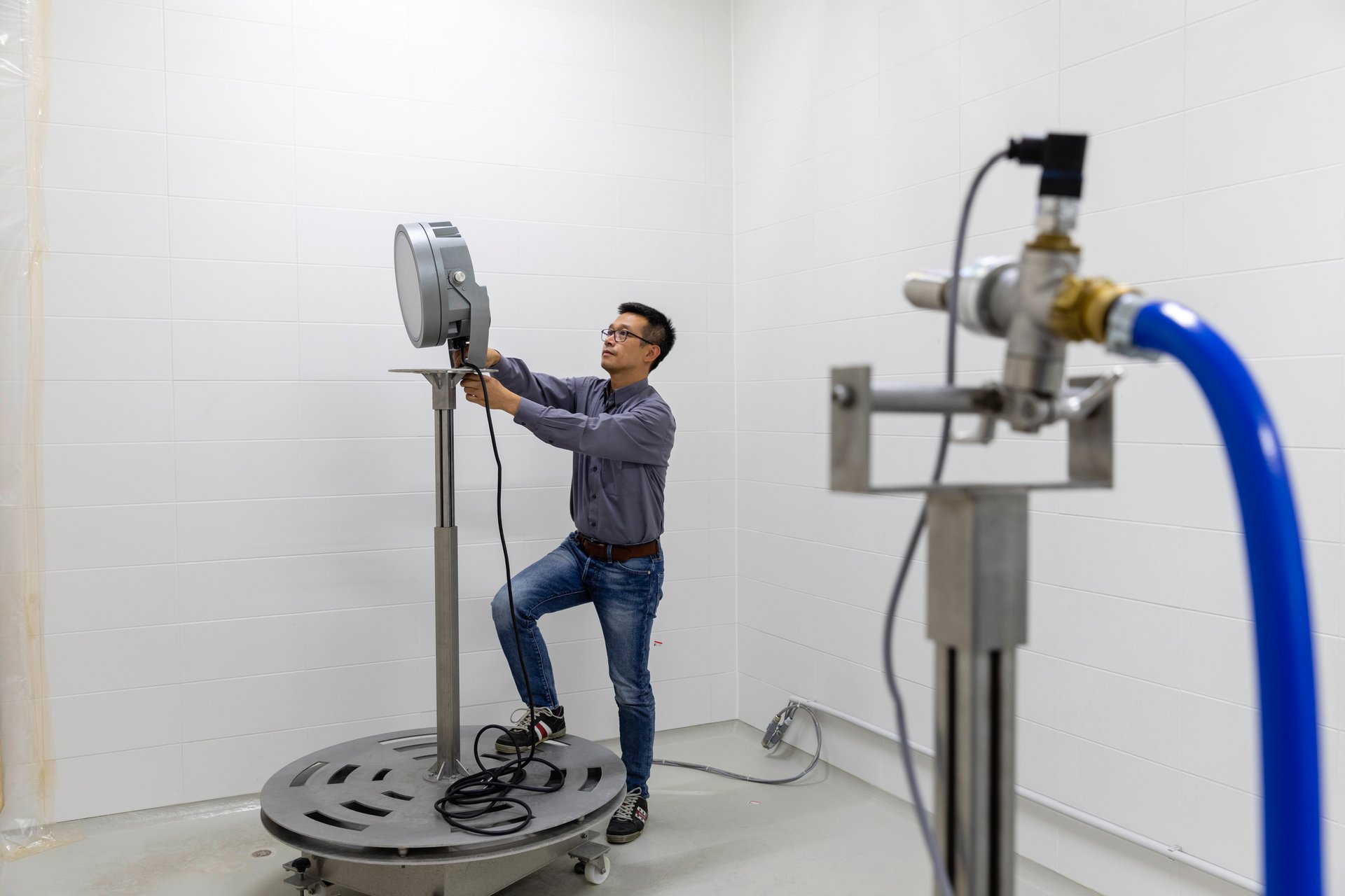 Ingénieur WE-EF montant un projecteur sur un banc d'essai rotatif dans une chambre d'essai d'étanchéité