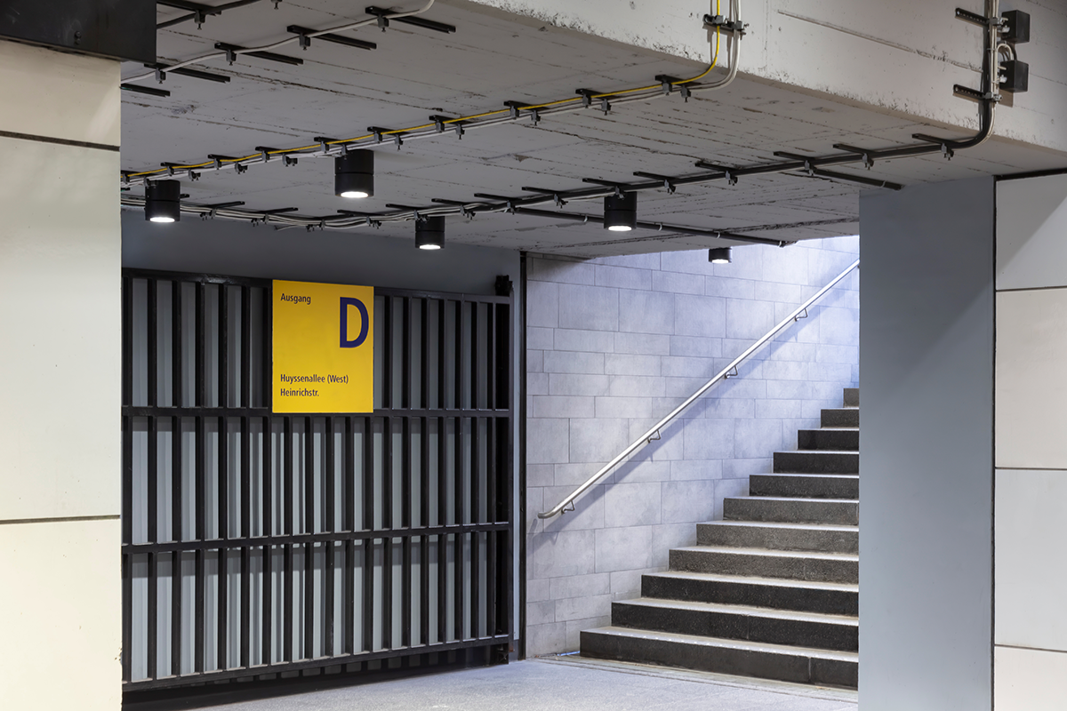 Aus Brandschutzgruenden wurden beim Umbau die Deckenverkleidungen entfernt, Leuchten und Kabel sind nun direkt auf der Betonkonstruktion montiert: eine ungewohnte, aber reizvolle technische Aesthetik. 