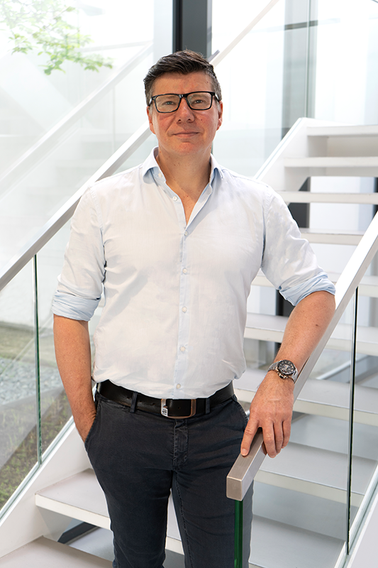 Portrait of Robert Diedrich, Global Head of Marketing at WE-EF Group, leaning on a handrail of a staircase at the company's head office.